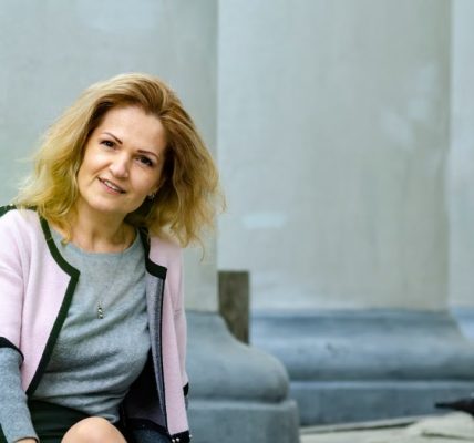 Woman sitting outdoors by classical columns in Lviv, Ukraine. Relaxed and elegant.
