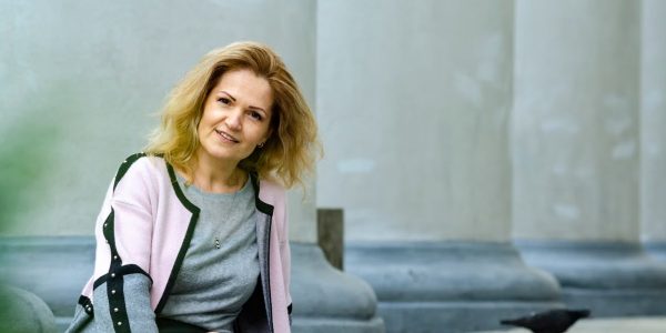 Woman sitting outdoors by classical columns in Lviv, Ukraine. Relaxed and elegant.